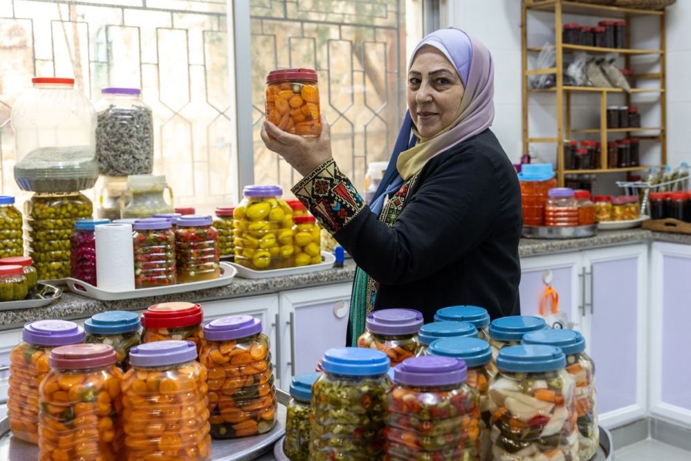 Lien vers le site du FIDA Une femme montre des produits dans des bocaux
