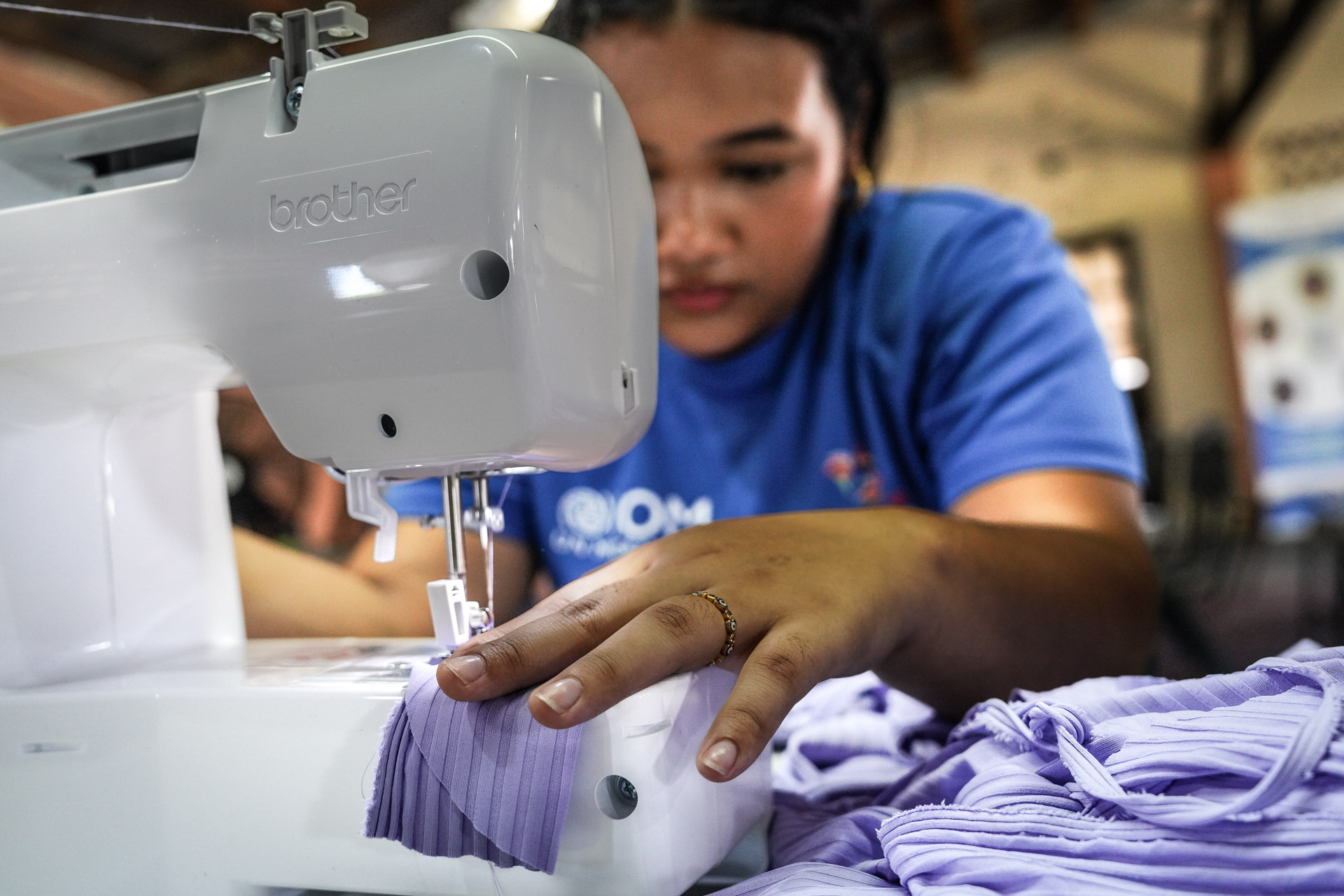 Lien vers le site de l'OIM Une femme derrière une machine à coudre