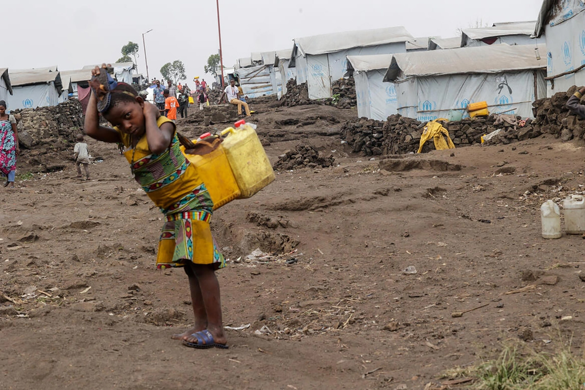 A girl carrying two water cans on her back.