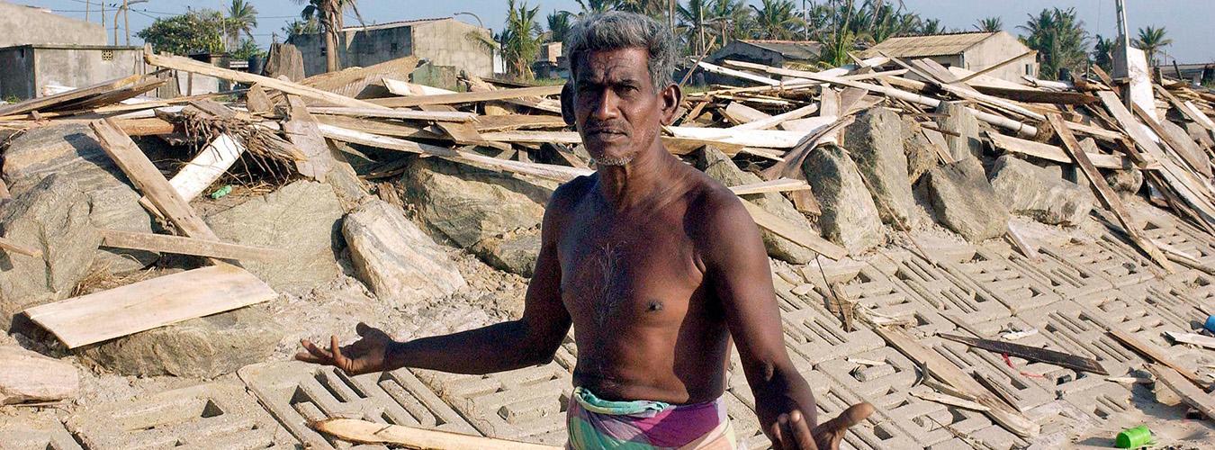 Un hombre se encuentra entre los escombros de su casa, destruida por un que fue destruida por un maremoto provocado por el sunami provocado por el tsunami del Océano Índico del 26 de diciembre de 2004.